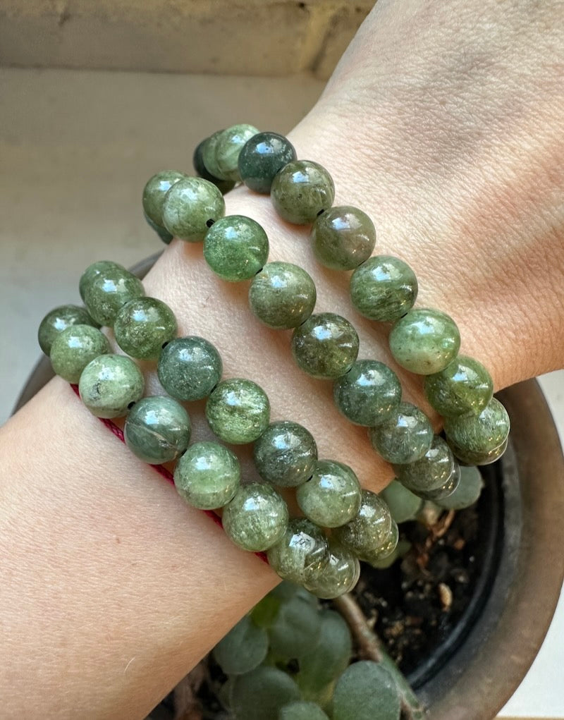 Green beaded bracelet on a wrist with a blurred background