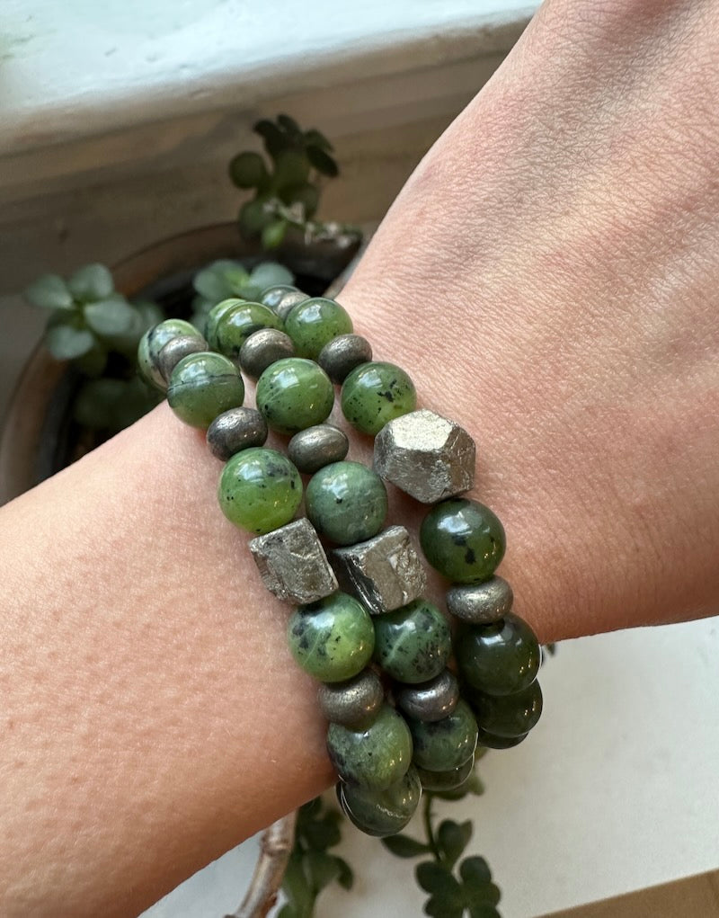 A bracelet made with round 8mm beads of jade and pyrite, displayed on a person's wrist.