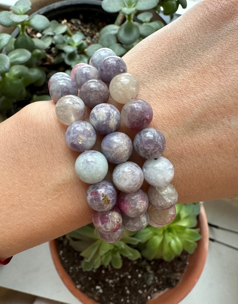 Multicolored beaded bracelet on a wrist with potted plants in the background
